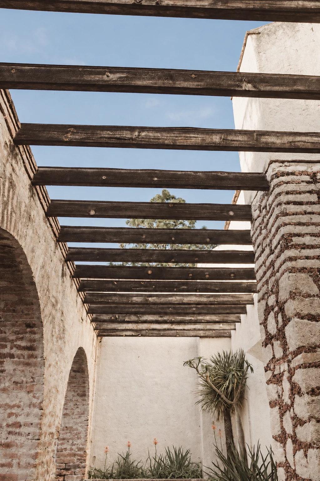 Fotografía retocada del patio de Hacienda Sepúlveda: vigas, arcos y muros de piedra.