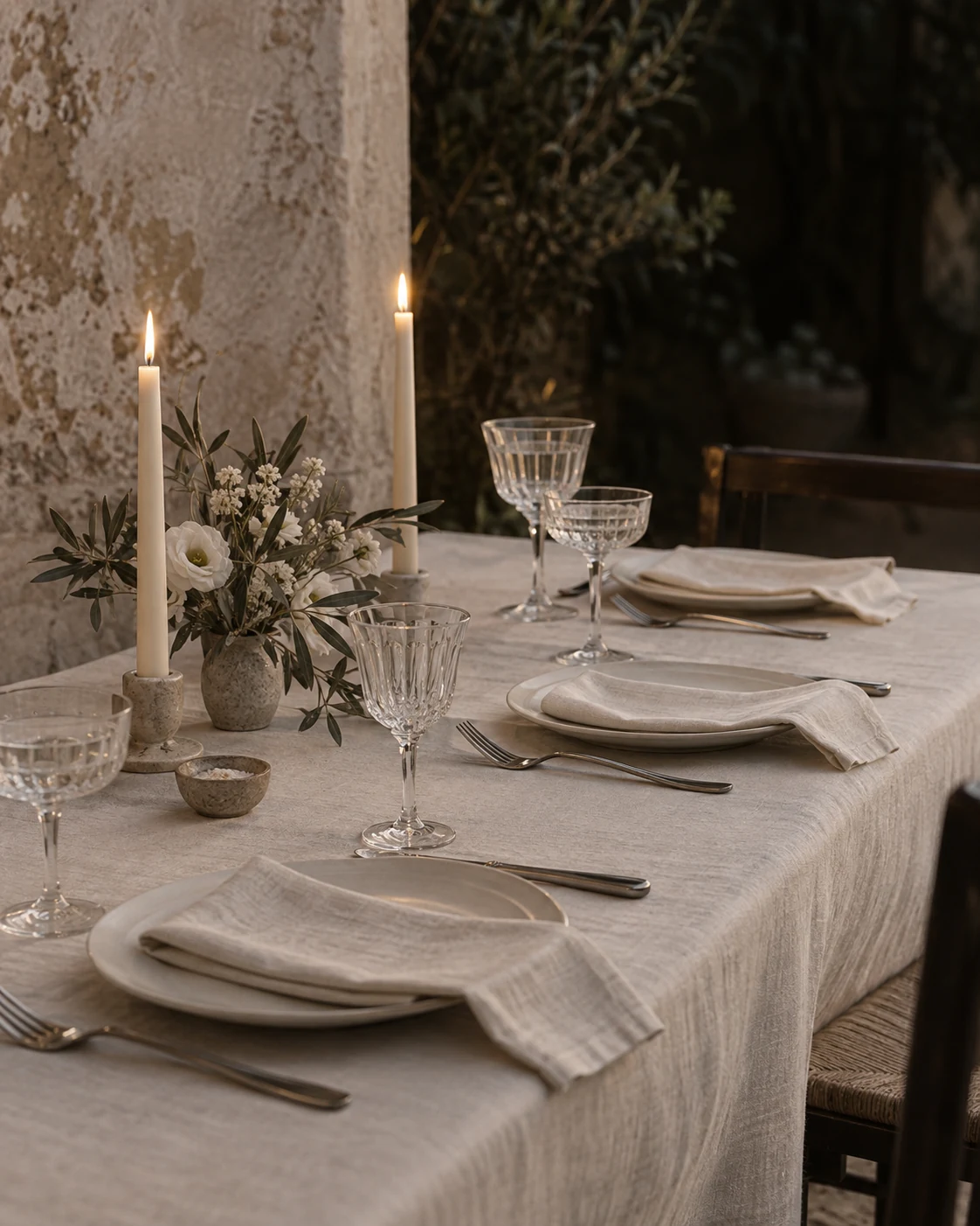 Imagen de ambientación de una mesa con lino marfil, cristal y velas; no representa el montaje definitivo.